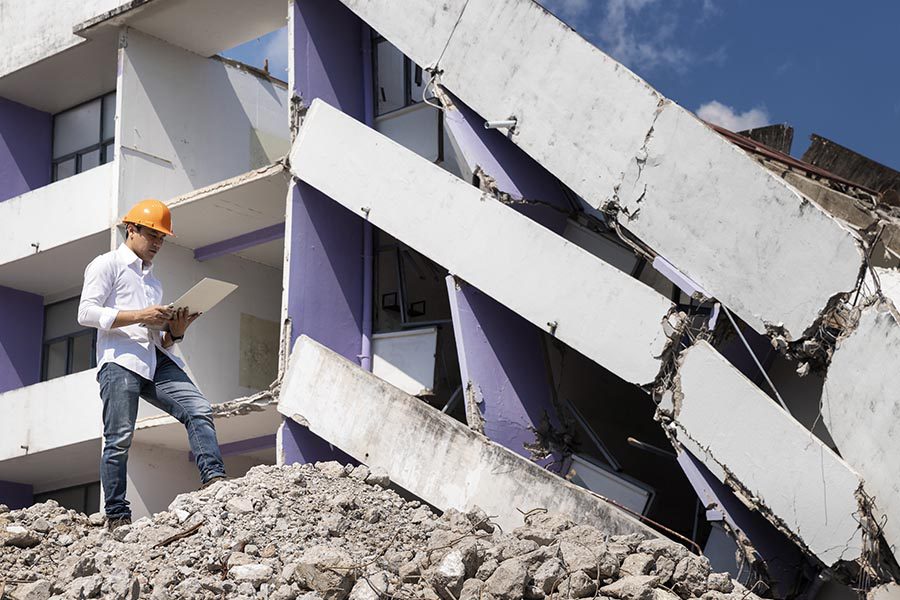 Natural Disaster Insurance - Engineer Looking Over the Rubble with an iPad in Hand